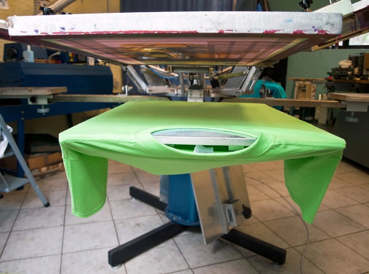 A green shirt is being folded on the ironing board.